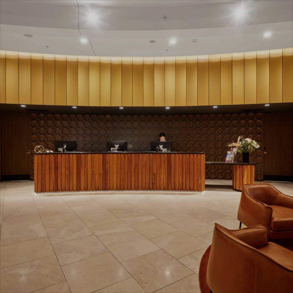 Luxury hotel reception desk with wooden slats and golden wall